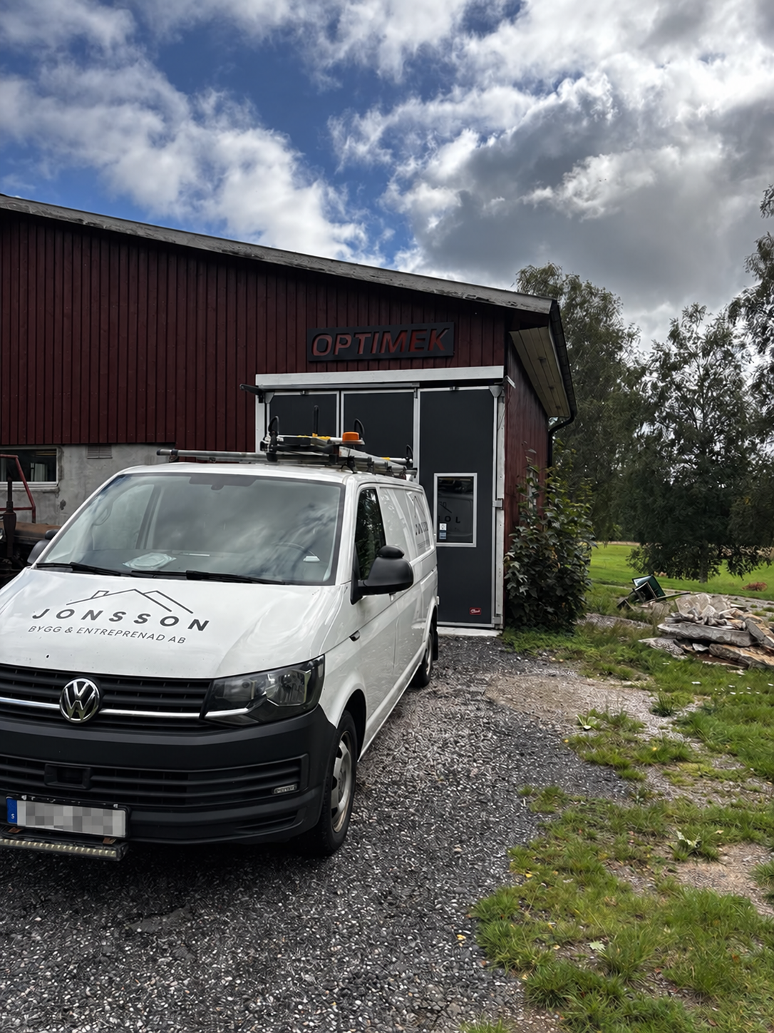 Volkswagen Transporter framför OptiMeks verkstad med dolt registreringsnummer
